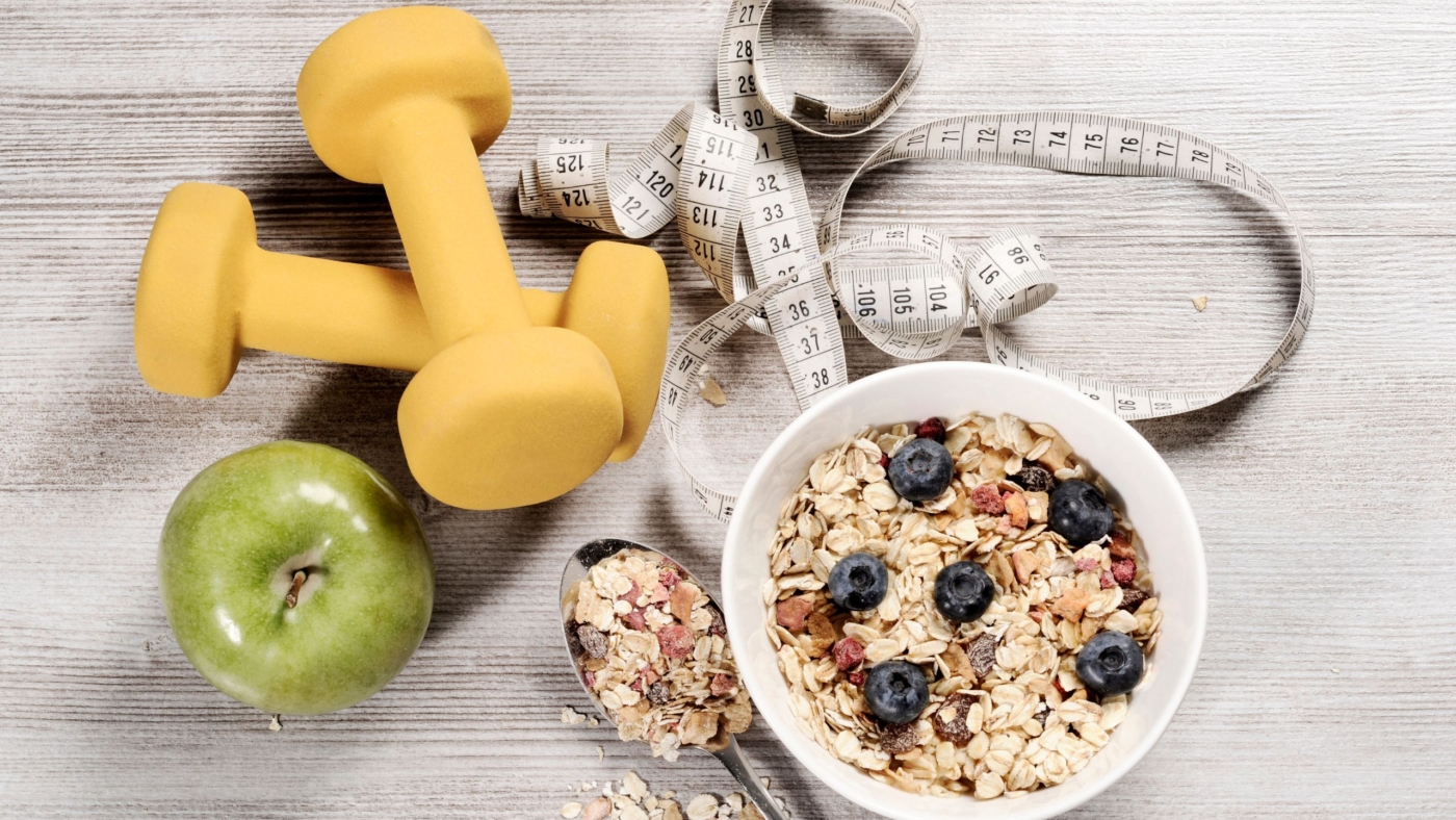 Dumbbells, oatmeal with blueberries, an apple and a measuring tape