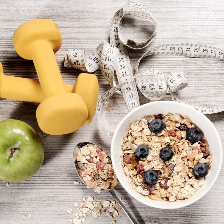 Dumbbells, oatmeal with blueberries, an apple and a measuring tape